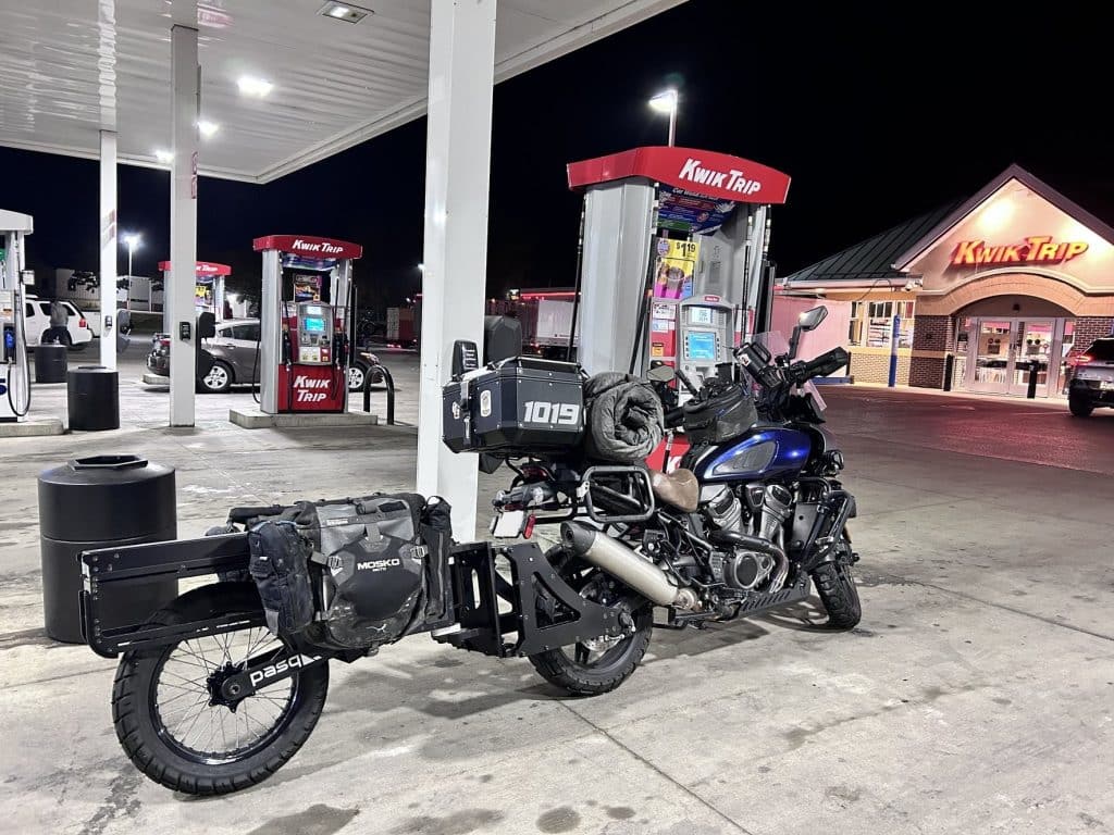 adv1 towed behind a motorcycle at a kwik trip gas station